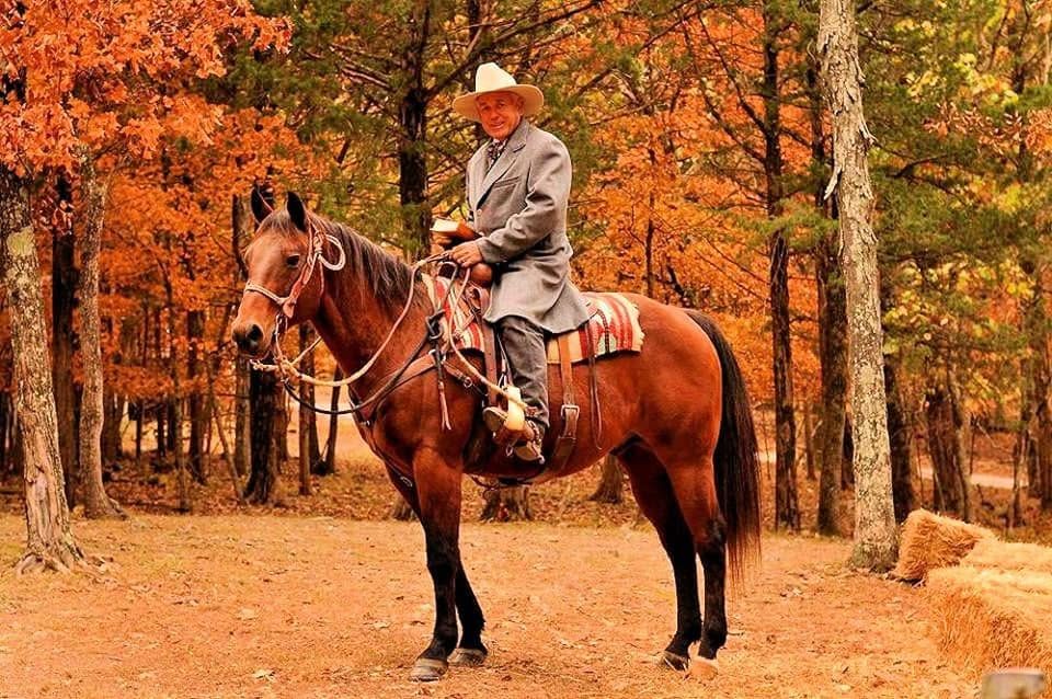 A costumed rider on horseback among blazing autumn trees at the Pioneer Village